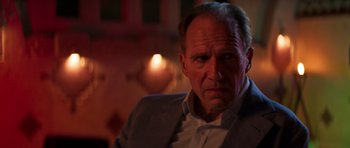 Movie still from “The Forgiven” (2021), directed by John Michael McDonagh – A person wearing a suit and tie; Close Up shot, Low angle