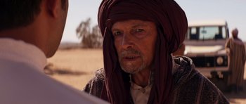 Movie still from “The Forgiven” (2021), directed by John Michael McDonagh – An older man with a beard and a turban; Close Up shot, Over the shoulder angle
