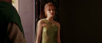 Movie still from “The Forgiven” (2021), directed by John Michael McDonagh – A woman in a green dress standing in front of a door; Medium shot, Low angle