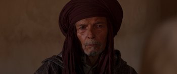 Movie still from “The Forgiven” (2021), directed by John Michael McDonagh – An old man wearing a turban and a scarf; Close Up shot, Over the shoulder angle