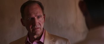 Movie still from “The Forgiven” (2021), directed by John Michael McDonagh – A person wearing a suit and tie; Close Up shot, Over the shoulder angle