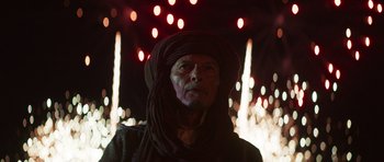 Movie still from “The Forgiven” (2021), directed by John Michael McDonagh – An old man wearing a turban and a scarf; Medium shot, Low angle
