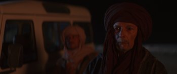 Movie still from “The Forgiven” (2021), directed by John Michael McDonagh – A man with a beard wearing a turban and a man with a beard wearing a head covering; Close Up shot, Over the shoulder angle