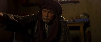 Movie still from “The Forgiven” (2021), directed by John Michael McDonagh – An old man wearing a turban is looking at the camera; Close Up shot, Over the shoulder angle