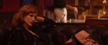 Movie still from “The Forgiven” (2021), directed by John Michael McDonagh – A woman sitting on a couch in front of a bar; Medium shot, Over the shoulder angle