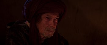 Movie still from “The Forgiven” (2021), directed by John Michael McDonagh – An old man with a beard and a head covering; Close Up shot, Over the shoulder angle