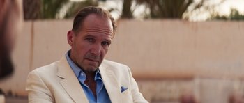 Movie still from “The Forgiven” (2021), directed by John Michael McDonagh – A person wearing a suit and tie; Close Up shot, Over the shoulder angle