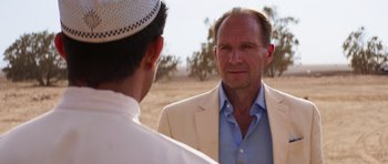 Movie still from “The Forgiven” (2021), directed by John Michael McDonagh – A man in a white jacket and a man in a blue shirt; Close Up shot, Over the shoulder angle