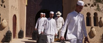 Movie still from “The Forgiven” (2021), directed by John Michael McDonagh – A group of men walking down a street with suitcases; Wide shot, Low angle