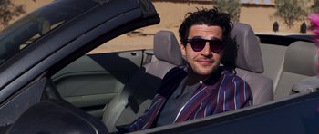 Movie still from “The Forgiven” (2021), directed by John Michael McDonagh – A man sitting in the driver's seat of a car; Medium shot, Low angle