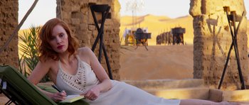 Movie still from “The Forgiven” (2021), directed by John Michael McDonagh – A woman is reading a book in the desert; Wide shot, Over the shoulder angle