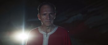 Movie still from “The Forgiven” (2021), directed by John Michael McDonagh – A man in a red and white shirt is standing in the dark; Close Up shot, Low angle