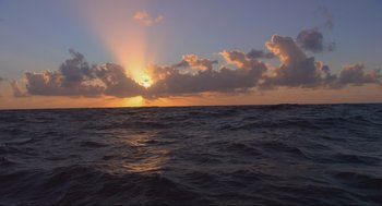 Movie still from “The Fourth Phase” (2016), directed by Jon Klaczkiewicz – The sun is setting over the ocean as seen from a boat; Extreme Wide shot, High angle