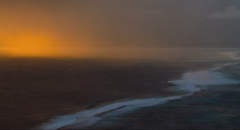Movie still from “The Fourth Phase” (2016), directed by Jon Klaczkiewicz – A view of the ocean at sunset from a plane window; Extreme Wide shot, High angle