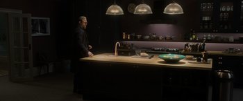 Movie still from “The Gentlemen” (2019), directed by Guy Ritchie – A man standing in front of a kitchen counter; Wide shot, High angle