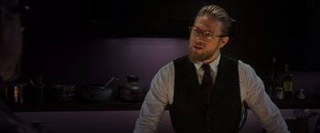 Movie still from “The Gentlemen” (2019), directed by Guy Ritchie – A man with a beard wearing a vest and tie; Medium shot, Over the shoulder angle