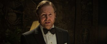Movie still from “The Gentlemen” (2019), directed by Guy Ritchie – A person wearing a suit and bow tie; Close Up shot, Low angle
