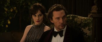 Movie still from “The Gentlemen” (2019), directed by Guy Ritchie – A man and a woman standing next to each other; Close Up shot, Low angle