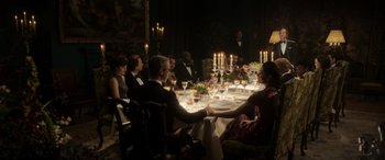 Movie still from “The Gentlemen” (2019), directed by Guy Ritchie – A group of people sitting around a dinner table; Wide shot, High angle