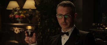 Movie still from “The Gentlemen” (2019), directed by Guy Ritchie – A man in a suit and tie holding a glass of wine; Close Up shot, Low angle
