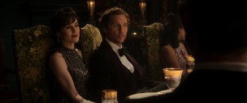 Movie still from “The Gentlemen” (2019), directed by Guy Ritchie – A man and a woman sitting at a dinner table; Medium shot, Low angle