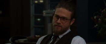 Movie still from “The Gentlemen” (2019), directed by Guy Ritchie – A man with a beard wearing glasses and a vest; Close Up shot, Over the shoulder angle