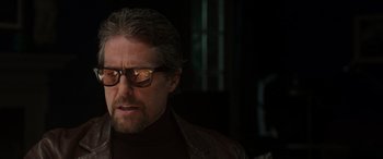 Movie still from “The Gentlemen” (2019), directed by Guy Ritchie – A person wearing sunglasses and a jacket; Close Up shot, Over the shoulder angle