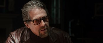 Movie still from “The Gentlemen” (2019), directed by Guy Ritchie – A person wearing sunglasses and a jacket; Close Up shot, Over the shoulder angle