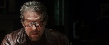 Movie still from “The Gentlemen” (2019), directed by Guy Ritchie – A person wearing glasses and a leather jacket; Close Up shot, Low angle