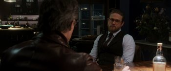 Movie still from “The Gentlemen” (2019), directed by Guy Ritchie – Two men sitting at a table in front of each other; Close Up shot, Over the shoulder angle