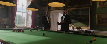 Movie still from “The Gentlemen” (2019), directed by Guy Ritchie – Two men in tuxedos playing a game of pool; Wide shot, Low angle
