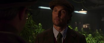 Movie still from “The Gentlemen” (2019), directed by Guy Ritchie – A person wearing a suit and a hat; Close Up shot, Over the shoulder angle
