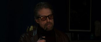 Movie still from “The Gentlemen” (2019), directed by Guy Ritchie – A person wearing glasses and holding a pipe; Close Up shot, Low angle