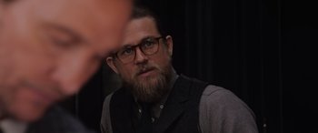 Movie still from “The Gentlemen” (2019), directed by Guy Ritchie – A man with a goatee wearing glasses and a vest; Close Up shot, Over the shoulder angle