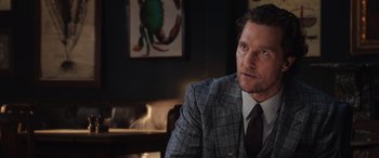 Movie still from “The Gentlemen” (2019), directed by Guy Ritchie – A person wearing a suit and tie; Close Up shot, Over the shoulder angle