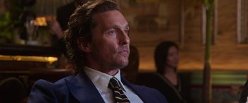 Movie still from “The Gentlemen” (2019), directed by Guy Ritchie – A person wearing a suit and tie; Close Up shot, Over the shoulder angle