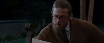 Movie still from “The Gentlemen” (2019), directed by Guy Ritchie – A man with a beard wearing glasses and a sweater; Close Up shot, Over the shoulder angle