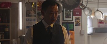 Movie still from “The Gentlemen” (2019), directed by Guy Ritchie – A man wearing a black vest and a black tie; Close Up shot, Low angle