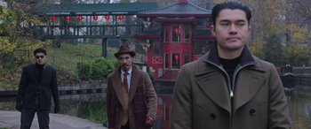 Movie still from “The Gentlemen” (2019), directed by Guy Ritchie – A man in a hat and coat walking next to another man in a hat; Medium shot, Over the shoulder angle