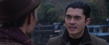 Movie still from “The Gentlemen” (2019), directed by Guy Ritchie – A man in a brown jacket talking to another man in a brown hat; Close Up shot, Over the shoulder angle