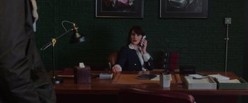 Movie still from “The Gentlemen” (2019), directed by Guy Ritchie – A woman sitting at a table talking on the phone; Medium shot, Low angle