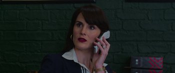 Movie still from “The Gentlemen” (2019), directed by Guy Ritchie – A woman in a suit talking on a cell phone; Close Up shot, Low angle
