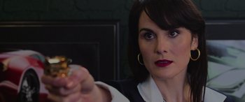 Movie still from “The Gentlemen” (2019), directed by Guy Ritchie – A person holding something in her hand; Close Up shot, Over the shoulder angle