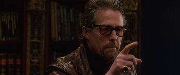 Movie still from “The Gentlemen” (2019), directed by Guy Ritchie – A person wearing glasses and a leather jacket; Close Up shot, Over the shoulder angle