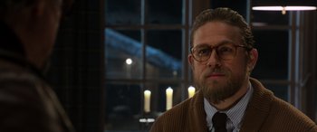 Movie still from “The Gentlemen” (2019), directed by Guy Ritchie – A man with a goatee wearing glasses and a sweater; Close Up shot, Over the shoulder angle