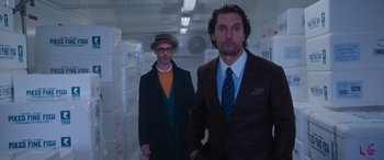 Movie still from “The Gentlemen” (2019), directed by Guy Ritchie – A man in a suit and a man in a hat; Medium shot, Low angle