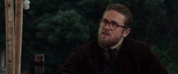 Movie still from “The Gentlemen” (2019), directed by Guy Ritchie – A man with a goatee and a beard wearing glasses; Close Up shot, Over the shoulder angle