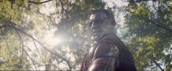 Movie still from “Deadpool 2” (2018), directed by David Leitch – A statue of a man in a suit is in front of a tree; Close Up shot, Low angle
