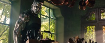Movie still from “Deadpool 2” (2018), directed by David Leitch – A man standing in front of a window in a kitchen; Medium shot, Low angle