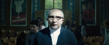 Movie still from “Deadpool 2” (2018), directed by David Leitch – An older man with glasses and a bald head in front of a group of people; Close Up shot, Low angle